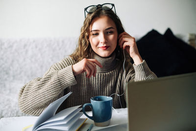 Portrait of young woman using laptop at home