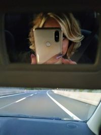 Man photographing through smart phone in car