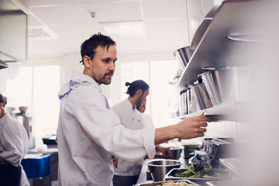 Young male chef reading order ticket in commercial kitchen