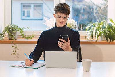 Goal-oriented businessman is on the phone with his supervisor, jotting notes in his diary