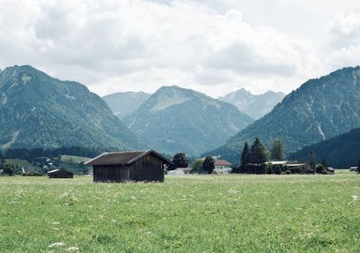 Houses on field by mountains against sky