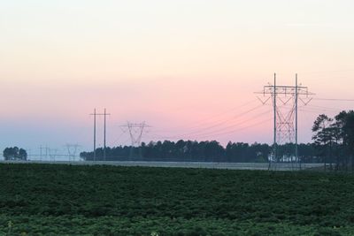 Electricity pylon on field against sky during sunset