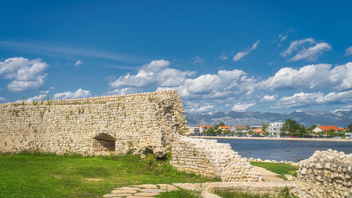 Built structure by sea against sky