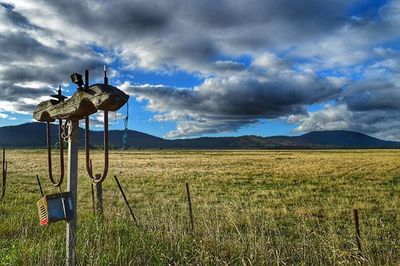 Scenic view of grassy field against cloudy sky