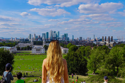 Rear view of woman looking at city buildings against sky