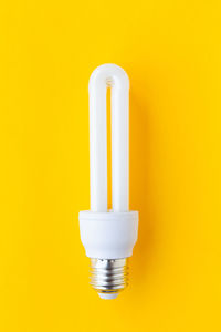 Close-up of light bulb against yellow background