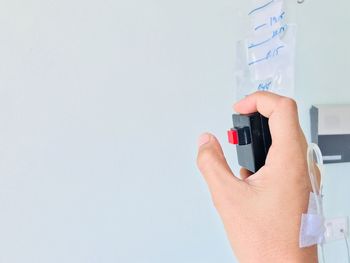 Close-up of hand holding camera against wall