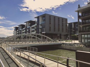 Bridge over canal by buildings against sky