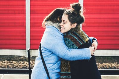 Friends embracing against red wall