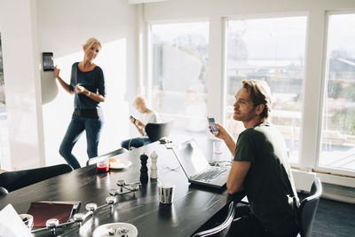 Mature woman standing by son looking at man in room