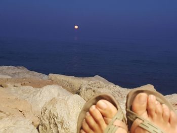 Low section of person on beach against sky