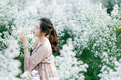 Side view of woman smelling white flowering plant