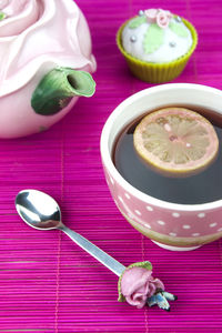 High angle view of tea with cupcake and spoon on place mat