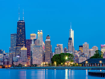 Illuminated buildings in city against clear sky