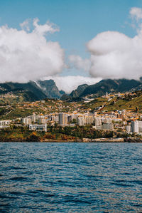 Scenic view of sea by buildings against sky