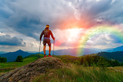 Man in the mountains at sunset looks rainbow in a divine sky