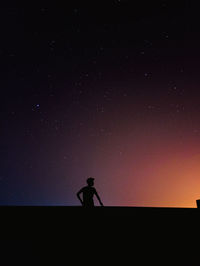 Silhouette man standing on field against sky at night