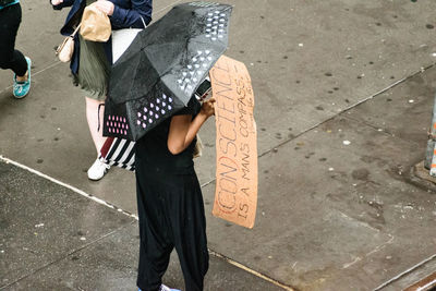 Low section of man standing with umbrella