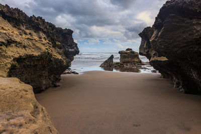 Rock formations on beach against sky