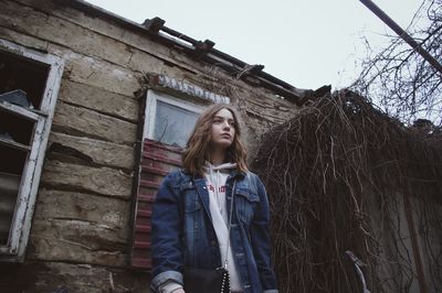 Portrait of young woman standing against building