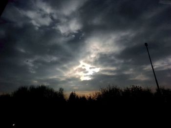 Silhouette of trees against cloudy sky