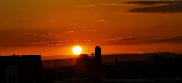 Silhouette buildings against orange sky