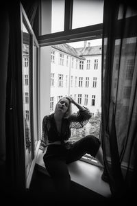 Woman looking through window at home