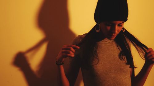 Portrait of woman standing against orange wall