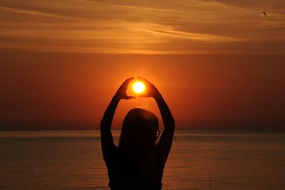 Close-up of hand holding sun at beach during sunset