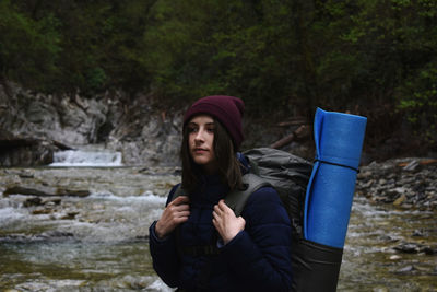 Backpacker walking against stream in forest