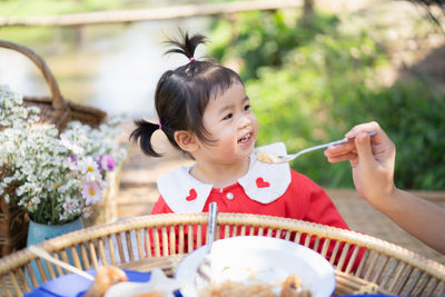 Cropped hand of mother feeding girl while sitting at park