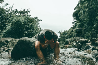 Man washing face while sitting in river