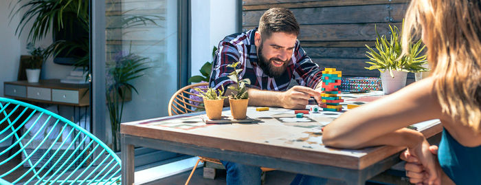 Bearded man catching jenga game piece with colleague on terrace