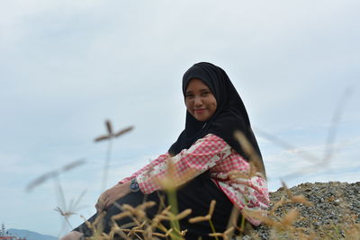 Smiling woman in park against sky during winter