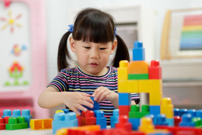 Young girl playing toy blocks at home 