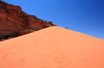 Low angle view of desert against clear blue sky