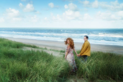 Friends enjoying at beach against sky