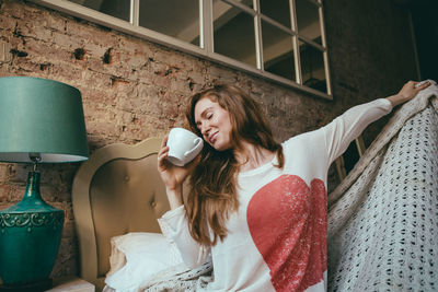 Woman stretching while having coffee at home