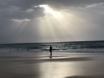 Silhouette person standing at beach against sky