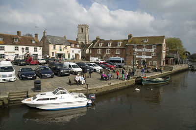 Boats moored on river by buildings against sky