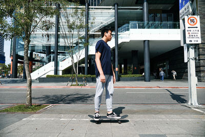 Full length of man skateboarding on street in city