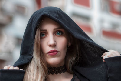 Close-up portrait of young woman in hooded shirt