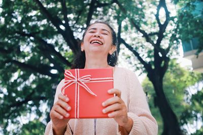 Smiling senior woman holding red gift box.