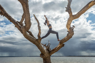 Woman standing in a tree, yoga pose, getting away from it all concept.