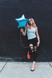 Portrait of young woman standing against wall