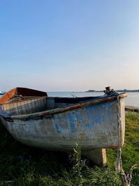 Abandoned boat moored on beach against clear sky