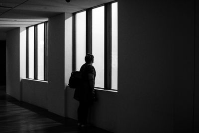 Rear view of man standing by window in building