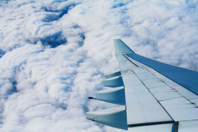 View of airplane wing flying over clouds