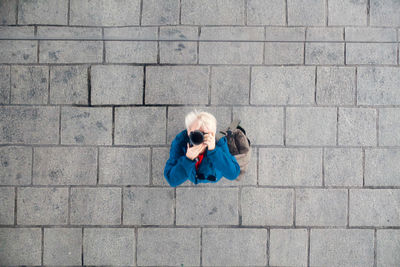 Overhead view of woman photographing while standing at paving stones