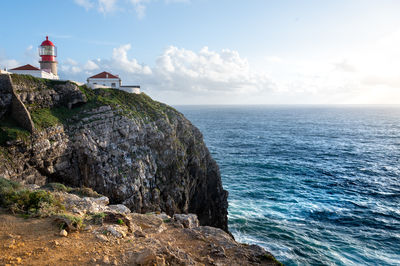 Lighthouse by sea against sky